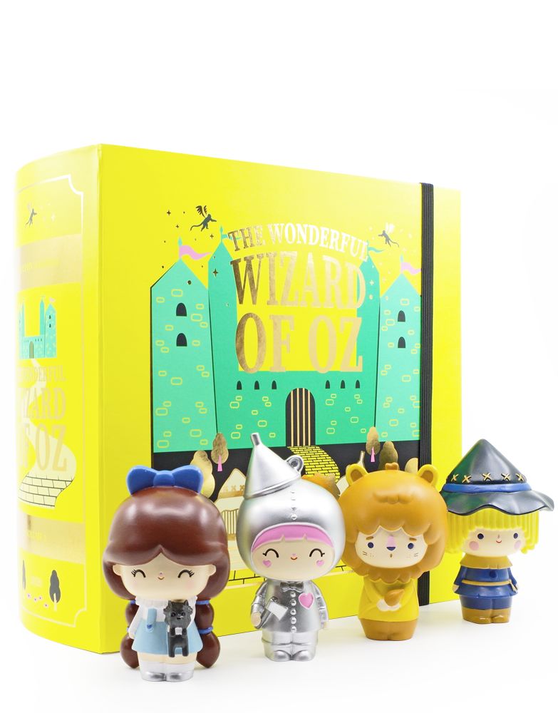 Four Wizard of Oz Momiji dolls stand before a large yellow Limited Edition book, The Wonderful Wizard of Oz. — Momiji doll