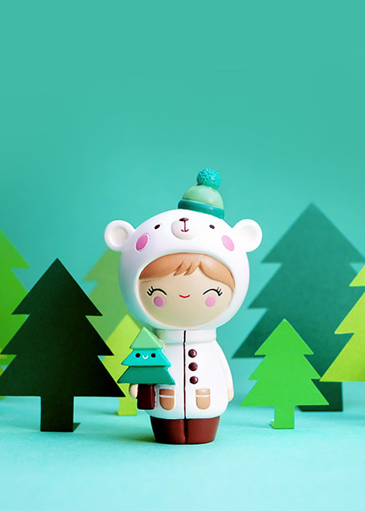 Parker Momiji doll in a bear hoodie holds a tiny tree, surrounded by paper trees on a turquoise background. — Momiji doll