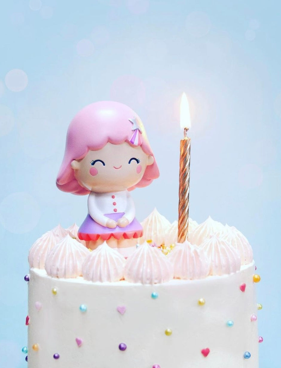 The Birthday Girl Rose Momiji doll and a lit candle on a white cake with colorful sprinkles. — Momiji doll