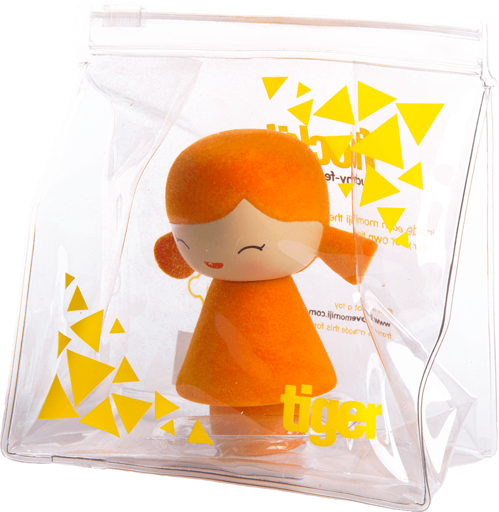 A small orange Tiger Momiji doll with closed eyes, packed in a clear zippered bag decorated with yellow triangles. — Momiji doll